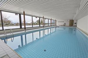a large swimming pool with blue tile floors and windows at Chaleureux studio proche des pistes de ski in Nendaz