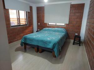 1 dormitorio con cama y pared de ladrillo en Casa Rural Poblado de Acha Arica en Arica