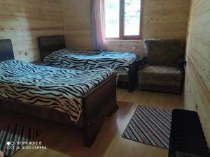 2 camas en una habitación con silla y ventana en Guesthouse Luka, en Ushguli