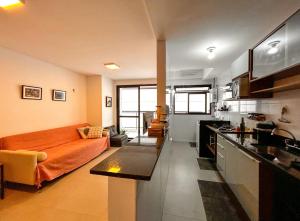 uma sala de estar com um sofá laranja e uma cozinha em Apto a 200m do mar em Niteroi Rio de Janeiro em Niterói