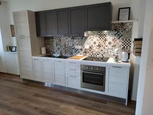 a kitchen with white cabinets and a stove top oven at Accogliente bilocale comodo per aeroporto e centro in Caselle Torinese