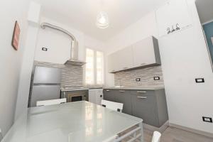 a white kitchen with a table and a refrigerator at Lauretta: Appartamento adiacente metro in Genoa