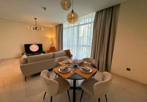 een woonkamer met een tafel en stoelen en een bank bij EasyGo - Polo Residence 1 Bedroom Community View in Dubai