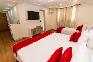 a bedroom with two beds and a flat screen tv at Granlago Hotel in Pouso Alegre