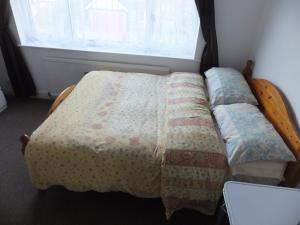 a bed with a quilt on it in a bedroom at 15 mins from East Croydon to Central London, Gatwick - Sleeps up to 7 couples plus Babies - Free WiFi, Parking - Next to Lloyd Park, Great for Walkers - Ideal for Contractors - Families - Relocators in Croydon