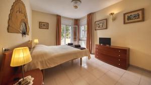 Schlafzimmer mit einem Bett und einer Kommode mit einem TV in der Unterkunft Costacabana - Villa Miro in Lloret de Mar
