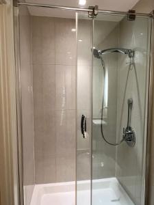 ducha con puerta de cristal junto a la bañera en Wood studio flat en Londres