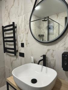 a bathroom with a white sink and a mirror at Chudodiyevo Park- Hotel in Vyshpolʼ