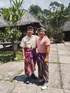 Dos personas posando para una foto frente a un edificio en Buana Asti Homestay en Tabanan
