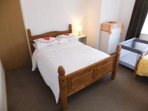 a bedroom with a wooden bed with white sheets and pillows at Exceptional Rated 10, 15 mins from East Croydon to Central London, Gatwick - Spacious, Sleeps up to 16 plus Cot - Free WiFi, Parking - Next to Lloyd Park, Great for Walkers - Ideal for Contractors - Families - Relocators in Croydon