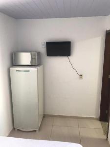 um quarto com um frigorífico e uma televisão na parede em Suítes Brisa Tropical em Cabo Frio