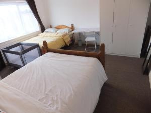 a bedroom with two beds and a table and a window at Exceptional Rated 10, 15 mins from East Croydon to Central London, Gatwick - Spacious, Sleeps up to 16 plus Cot - Free WiFi, Parking - Next to Lloyd Park, Great for Walkers - Ideal for Contractors - Families - Relocators in Croydon