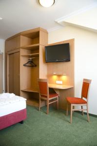 Habitación con escritorio, 2 sillas y TV. en Hotel Rosner en Gablitz