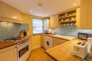 a kitchen with a sink and a stove top oven at Corner Cottage - The Pink House in Southwold