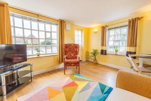 a living room with a chair and a television at Corner Cottage - The Pink House in Southwold