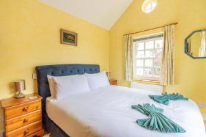 a bedroom with a bed with a blue headboard and a window at Corner Cottage - The Pink House in Southwold