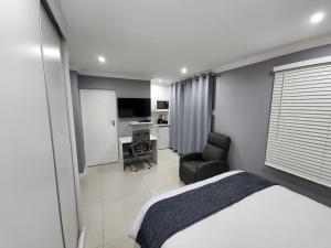 een slaapkamer met een bed, een stoel en een bureau bij Vusi's Guesthouse in Durban
