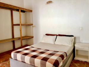 a bedroom with a bed with a checkered blanket at Casa Caracolí in Villanueva