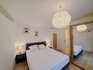 - une chambre avec un grand lit blanc et un miroir dans l'établissement Antibes, duplex lumineux, à Reims