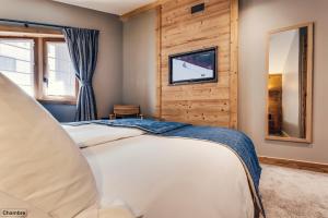 1 dormitorio con 1 cama y TV en la pared en Hôtel Avancher, en Val dʼIsère