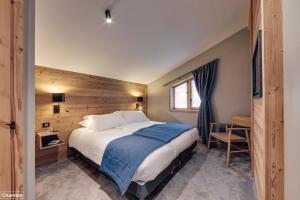 1 dormitorio con 1 cama grande y pared de madera en Hôtel Avancher en Val dʼIsère