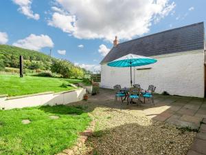 un patio con una mesa y una sombrilla azul en 3 Bed in Abergavenny BN324 en Abergavenny
