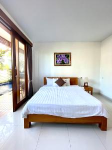 sypialnia z dużym łóżkiem i oknem w obiekcie Bali Ayu Pool Villa w mieście Canggu