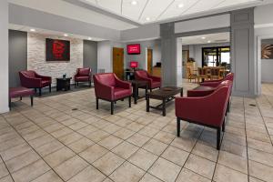 a waiting area in a hospital with red chairs and tables at Red Roof Inn & Suites Monroe, NC in Monroe