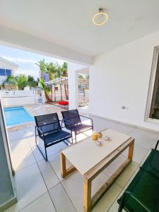 sala de estar con mesa, sillas y piscina en Beach Villa With Private Pool And BBQ en Lárnaca
