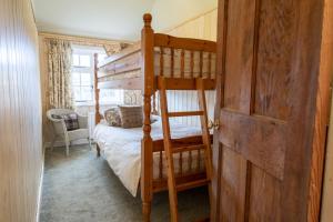 1 Schlafzimmer mit 2 Etagenbetten und einer Tür in der Unterkunft Acorn Cottage in Bolton Bridge