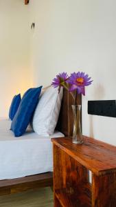 a vase with purple flowers sitting on top of a table at The Point Mirissa in Mirissa