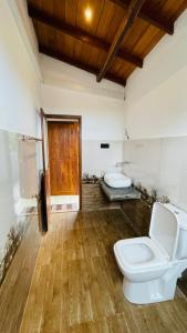 a bathroom with a toilet and a wooden floor at The Point Mirissa in Mirissa