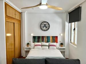 1 dormitorio con 1 cama con reloj en la pared en Apartamentos Malasaña, en Madrid