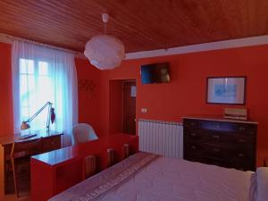 Schlafzimmer mit roten Wänden, einem Bett und einem Schreibtisch in der Unterkunft Casa Pini Rio_A in Riolunato