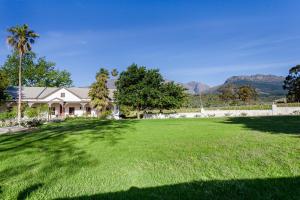 un gran patio con una casa y un gran césped en Nabygelegen Gate house, en Bainʼs Kloof