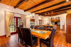 a dining room with a wooden table and black chairs at Nabygelegen Gate house in Bainʼs Kloof