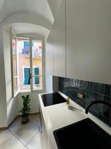 eine weiße Küche mit einem Waschbecken und einem Fenster in der Unterkunft BordiLand 1 in Bordighera