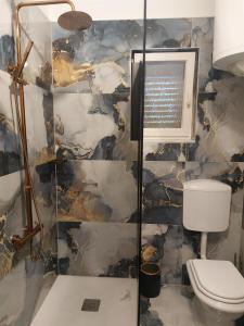 łazienka z toaletą i kamienną ścianą w obiekcie Apartments RUZA w Crikvenicy