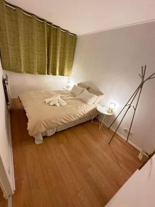 a bedroom with a bed and a lamp on a wooden floor at Jade Apart Bussy Centre Disney 10min in Bussy-Saint-Georges