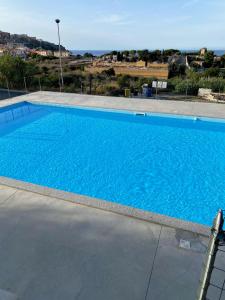 a large blue swimming pool with the ocean in the background at Casa Alexandra in Castelsardo