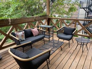 a wooden deck with chairs and tables on a porch at Hidden East Village Gem in Chicago