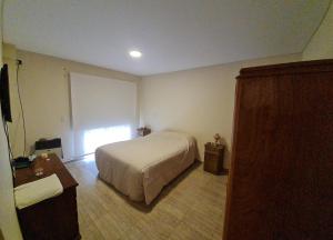 1 dormitorio con cama, mesa y ventana en Casa 6 pers. en Mendoza