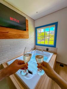 two people holding wine glasses in front of a tub at Hotel Pontal de Tiradentes in Tiradentes