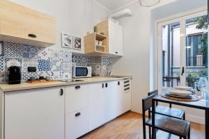 une cuisine avec des placards blancs et une table avec des chaises dans l'établissement Remy Studio - Design District, à Milan