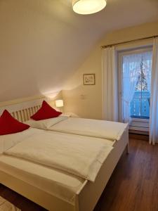 a bedroom with a bed with red pillows and a window at Haus am Mühlenweg - Appartement 4 Haus I - sonniges und modernes Ferienappartement in Bad Wörishofen