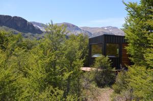 una casa negra en una colina con montañas al fondo en Cerro Electrico - Off The Grid Tiny Houses en El Chalten