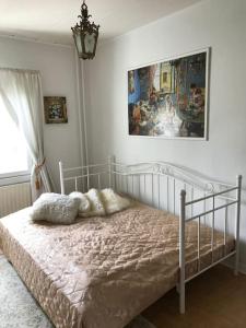 1 cama blanca en un dormitorio con una pintura en la pared en Romanttinen Retrokaksio, en Oulu