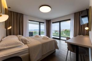 um quarto com uma cama, uma mesa e janelas em Luxury Villa Miamore em Kaštela