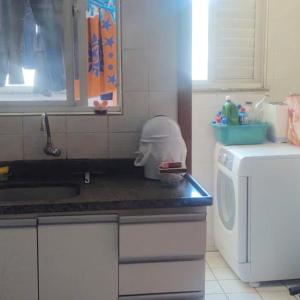 een keuken met een wastafel en een wasmachine bij 1 quadra e 1/2 do mar no Centro de Balneário Camboriú! in Balneário Camboriú