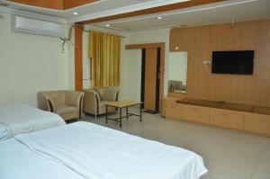 a hotel room with two beds and a flat screen tv at Hotal Balaji in Gwalior
